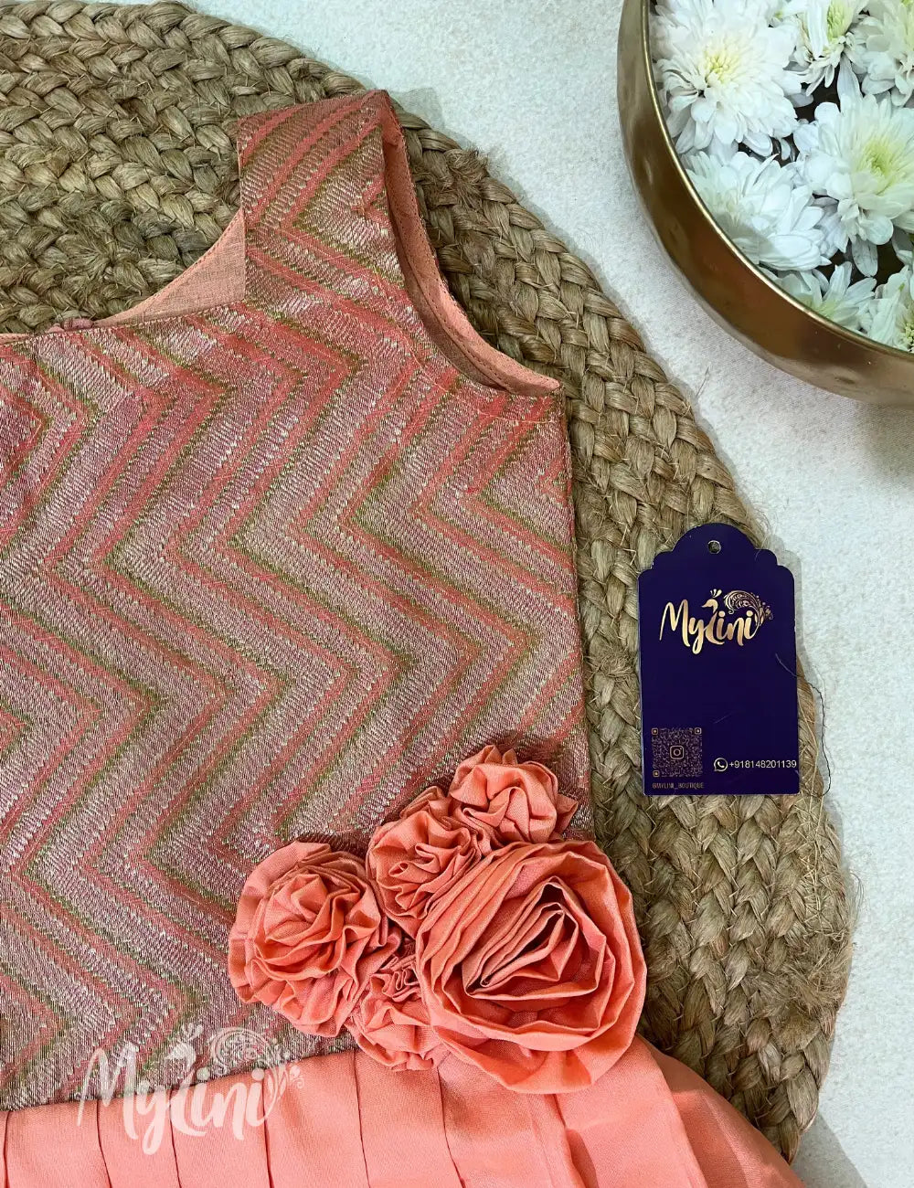 Young girl in a peach dress with floral details, holding toys, in a decorated room.